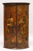 A 19TH CENTURY LACQUERED PINE BOWFRONT HANGING CORNER CUPBOARD, the pair of doors decorated in the