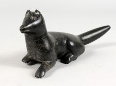 AN INUIT CARVED HARDSTONE GROUP OF A FOX LAYING DOWN. 9ins long.