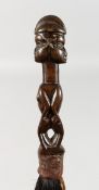 A NATIVE FLY WHISK, carved with two figures. 16ins long.