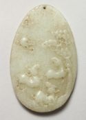A CHINESE OVAL CARVED CELADON JADE PENDANT. 3.25ins high.