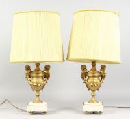 A PAIR OF GILDED SPELTER URN SHAPED TABLE LAMPS, on marble bases. 14ins high.