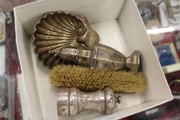 A silver pedestal sugar caster, a shell shaped butter dish, a pepper grinder and hand brush.