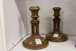 A pair of walnut and brass candlesticks.