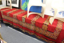 A large eastern rug, red ground with stylized banded decoration.