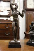 A bronze standing male nude on a square marble base.