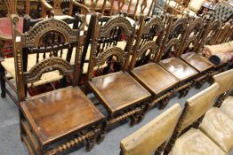 A set of six continental style oak dining chairs with carved back rails and solid seats.