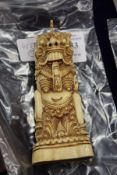 A bone carving of an Asian temple guardian figure.