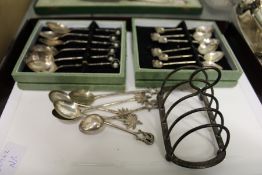 A silver toast rack and eastern white metal spoons.