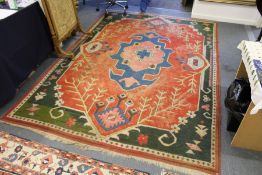 An eastern carpet, bright red ground with stylized blue, cream and green decoration (some wear).