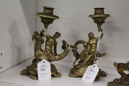 A pair of ornate cast brass figural candlesticks in the classical manner.