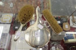 A plain silver backed hand mirror and two silver backed hand brushes.