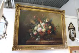 A still life of flowers in a vase on a ledge, oil on canvas, in a large decorative gilt frame.