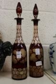 A pair of ruby coloured etched glass decanters (one neck repaired).