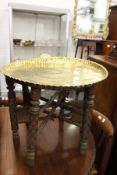 An eastern engraved brass tray top table with folding stand.