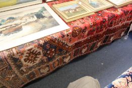 A Persian carpet, red ground with stylized decoration.