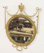 A decorative circular gilt framed mirror mounted with urns and swags.