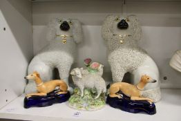A pair of Staffordshire spaniels, a pair of sheep spill vases and a pair of reclining greyhounds.
