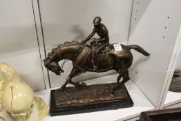 A bronze group of a jockey on horseback on a marble base.