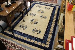 A Chinese rug, beige ground with eight floral motifs.