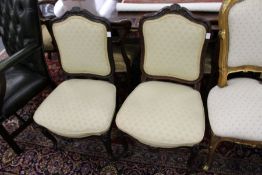 A pair of Victorian carved rosewood framed side chairs with upholstered backs and seats.