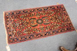 A small Persian rug, red ground with floral decoration.