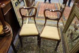 A pair of Victorian rosewood dining chairs with kidney backs, drop-in seats on turned and carved
