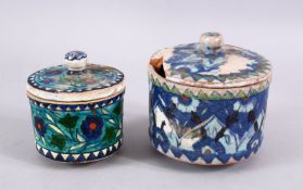 TWO EARLY TURKISH POTTERY LIDDED JARS, both decorated with floral design, 12cm & 10cm diameter.