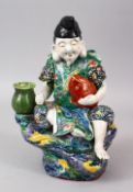 A GOOD JAPANESE MEIJI PERIOD KUTANI PORCELAIN FIGURE OF A GOD SEATED UPON A ROCK, holding his fish