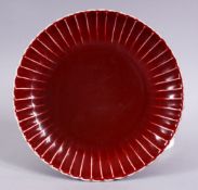 A CHINESE MING STYLE COPPER RED PORCELAIN RIBBED DISH, 21.5cm the base with a six character mark.