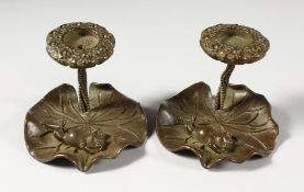 A SMALL PAIR OF BRONZE CANDLESTICKS, modelled as frogs on lily pads. 3ins wide.