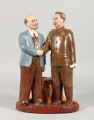 A RUSSIAN POTTERY GROUP, two figures standing shaking hands. 13.5ins high.