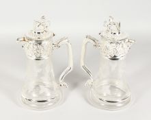 A PAIR OF ETCHED GLASS CLARET JUGS WITH PLATED MOUNTS AND LION FINIALS. 10.75ins high.