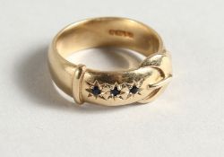 AN 18CT GOLD BUCKLE THREE STONE SAPPHIRE RING.