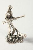 A MINIATURE SILVER FIGURE OF A MAN with a gun and a dog.