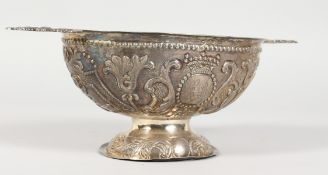 A DUTCH SILVER TWIN-HANDLED PEDESTAL BOWL/PORRINGER, with embossed and chased decoration. 9ins