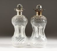 A PAIR OF HOURGLASS DECANTERS, with embossed silver rims and collars, London 1900. 8.5ins high.