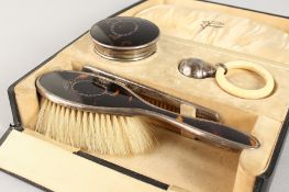 A VICTORIAN TORTOISESHELL AND SILVER BRUSH, POWDER POT, COMB AND SILVER TEETHING RING, in a fitted