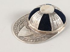 A NOVELTY SILVER JOCKEY CAP PIN CUSHION.