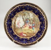 A VERY GOOD FRENCH ENAMEL CIRCULAR DISH, painted with a scene, lady on a swing with children. 5ins