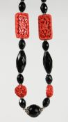 A CINNABAR LACQUER AND JET BEAD NECKLACE. 26ins long.