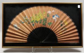 A LARGE CHINESE FRAMED AND GLAZED FAN, painted with birds and flowers. 33ins open.