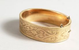 AN ENGRAVED GILT METAL BANGLE.