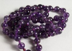 AN AMETHYST BEAD NECKLACE. 27ins long.