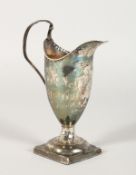 A GEORGE III HELMET SHAPED CREAM JUG on a square base. London 1784.