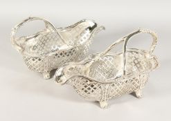 A GOOD PAIR OF PIERCED PLATE BOTTLE HOLDERS with acanthus scrolling handles, on four curving feet.