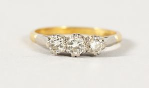 AN 18CT GOLD DIAMOND THREE STONE RING.