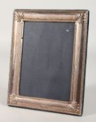 AN UPRIGHT PHOTOGRAPH FRAME with bead and shell border. 8.5ins x 6.5ins.