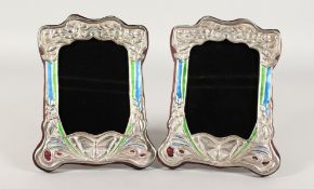 A PAIR OF SILVER AND COLOURED ENAMEL PHOTOGRAPH FRAMES with butterflies and flowers. 8.5ins x 6ins.