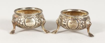 A SMALL PAIR OF VICTORIAN CIRCULAR SALTS, repousse body on three pad feet. London 1816.