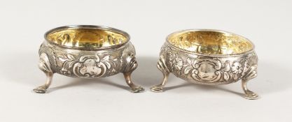 A PAIR OF GEORGE III CIRCULAR SALTS repousse body on three pad feet. London 1772.